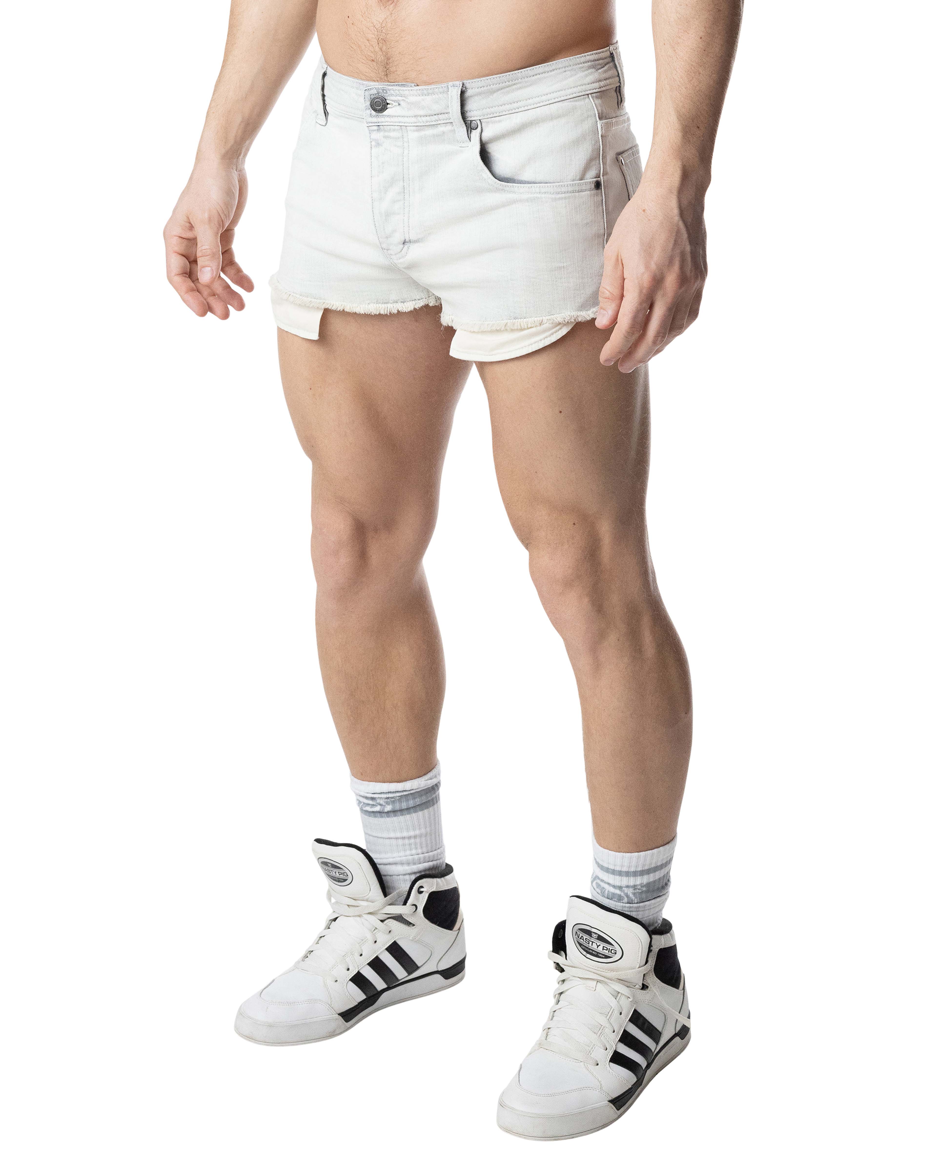 Person wearing white denim shorts and white sneakers on a white background