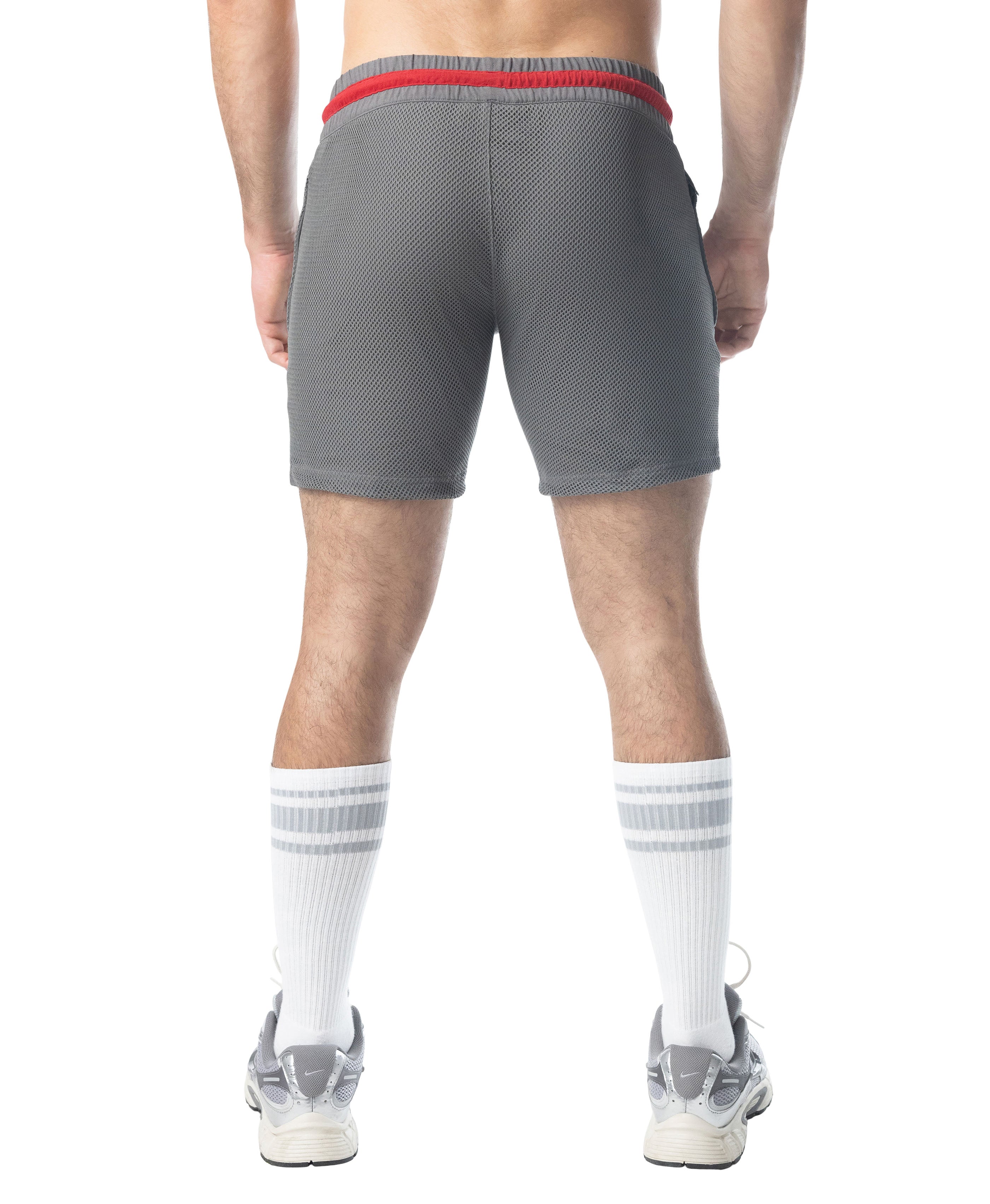 Person wearing gray athletic shorts with a red waistband on a white background