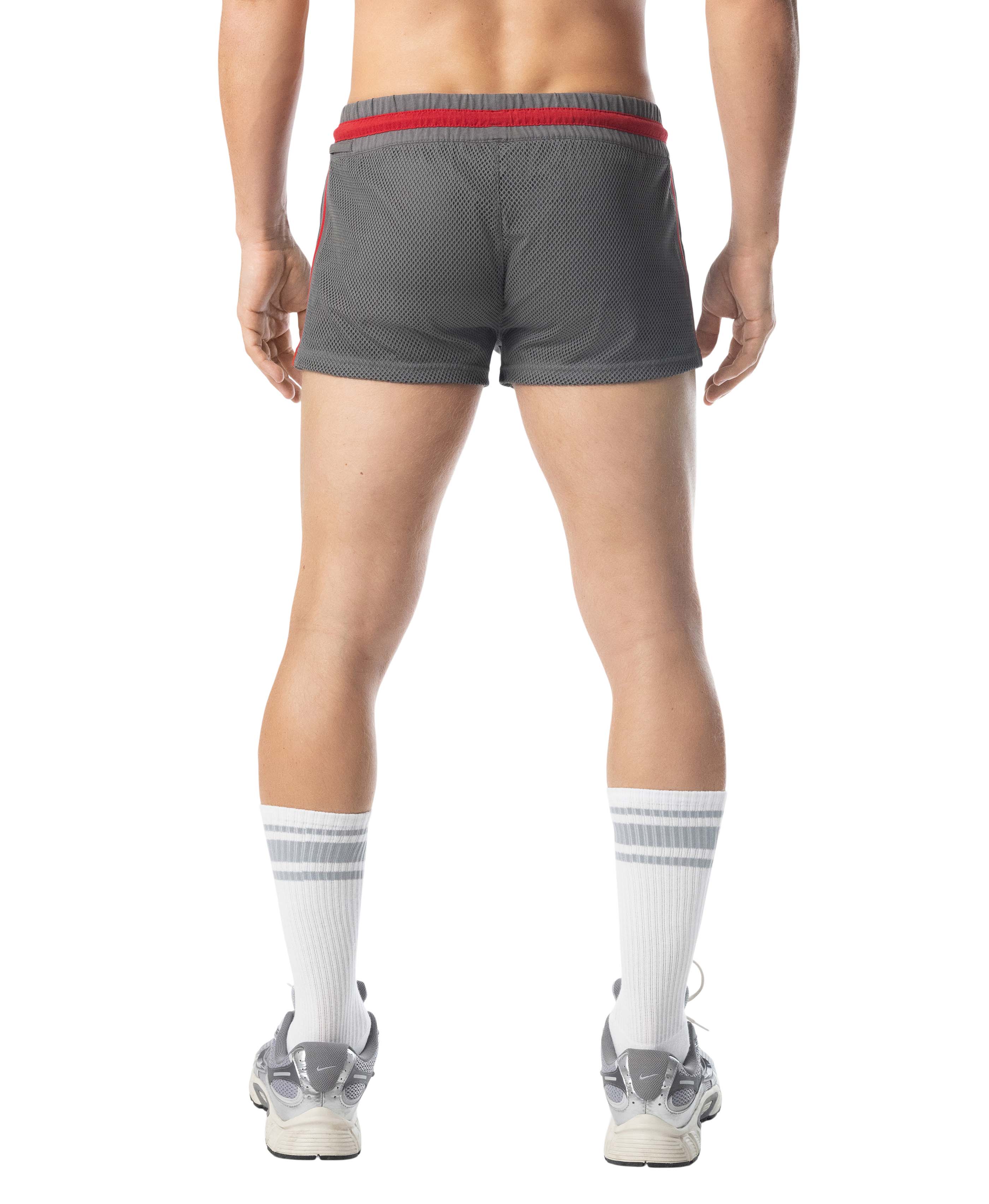 Person wearing gray athletic shorts with red waistband on a white background