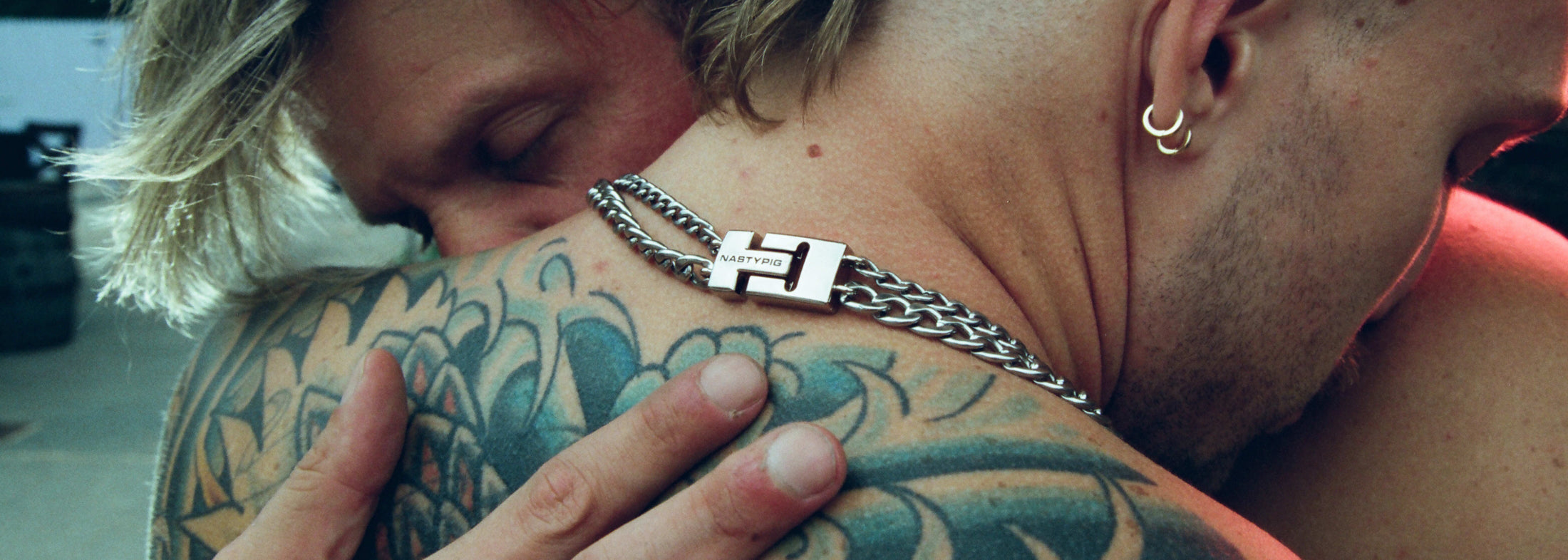 Two men embracing, Nasty Pig jewelry is visible