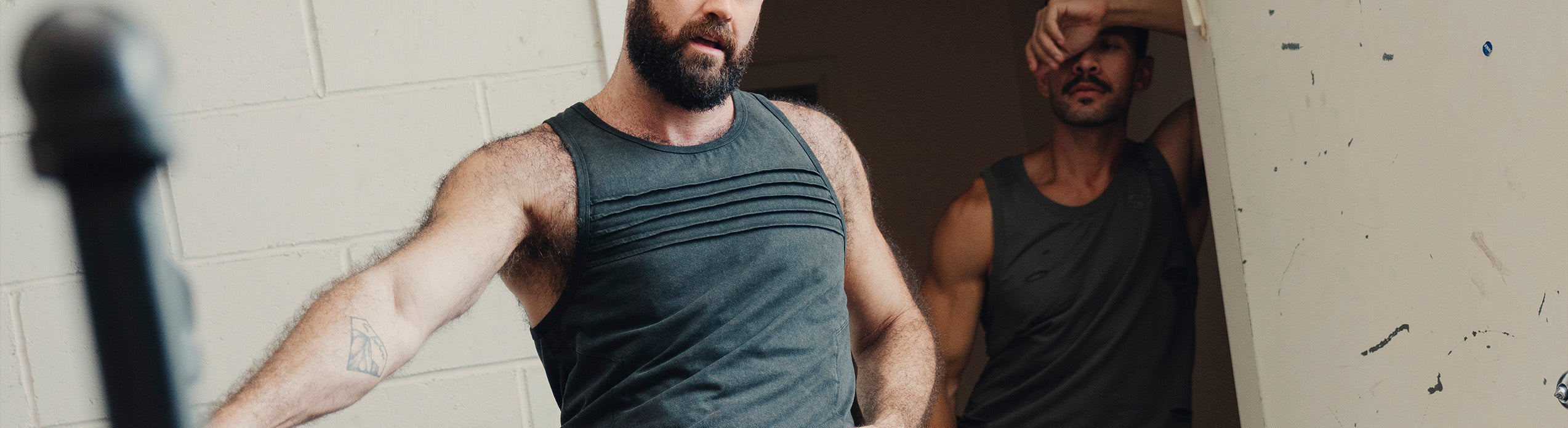Two men embracing while wearing tank tops