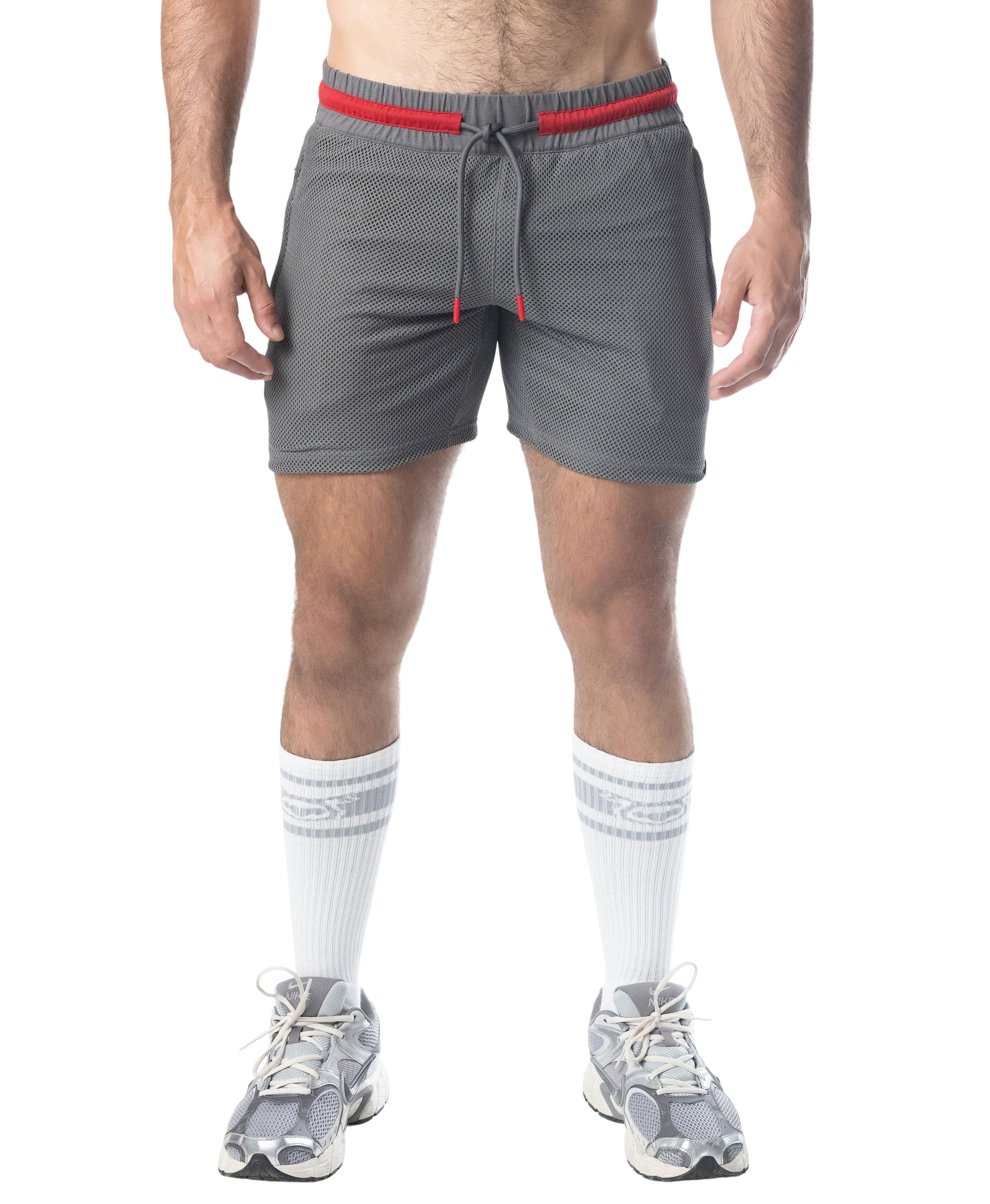 Person wearing gray shorts with red waistband and white socks on a white background
